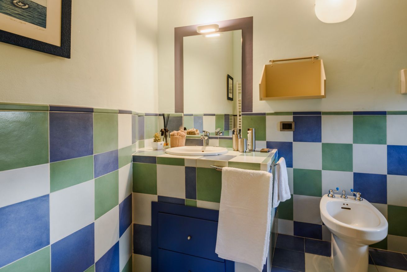 Een badkamer met een wand van zwart-wit geruite tegels, een wastafel, een spiegel, een handdoek en een douchetoilet.