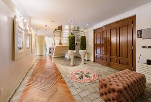 Un couloir doté d’un plancher en bois, d’un escalier en colimaçon, d’une grande porte en bois et d’un tapis rond.