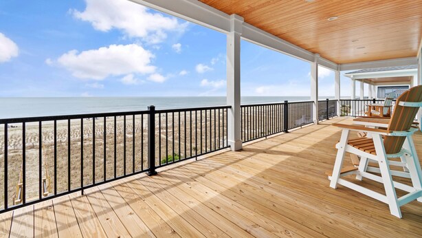 A wooden deck with a view of the beach and ocean.