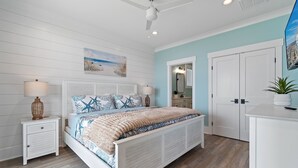 A bedroom with a bed, nightstand, lamp, and a ceiling fan.