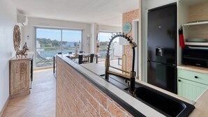 A modern kitchen with a brick backsplash, a black refrigerator, and a dining area with a view of the sea. - Le Fidji by Interhome (La Ciotat)