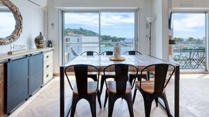 A dining area with a table and chairs, a view of the sea, and a large mirror on the wall. - Le Fidji by Interhome (La Ciotat)