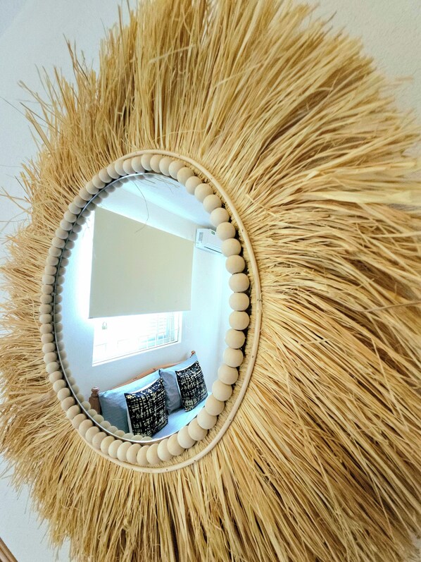 A mirror with a sunburst frame and a wall-mounted air conditioner.