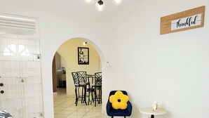 Een woonkamer met een bank, een klein tafeltje met een gele bloem, en een bord met de tekst 'thankful'.