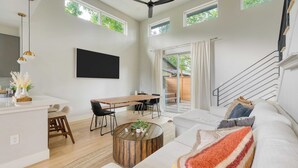 A spacious living area with a dining table, sofa, and a staircase. - Private Pool, Firepit, Patio Steps to East Austin Dining, Music, Art, Murals (Austin)