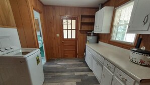 A kitchen with wooden walls, a white refrigerator, a sink, and cabinets. - Renovated rural 3-bedroom 2-bathroom ranch style home in Smithville, TN (Smithville)