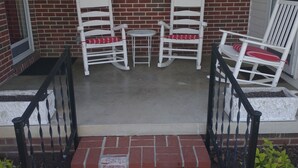 A brick exterior with a porch featuring white rocking chairs and a small table. - Renovated rural 3-bedroom 2-bathroom ranch style home in Smithville, TN (Smithville)