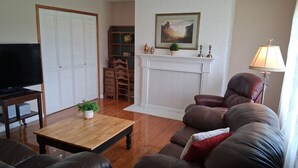 A living room with a fireplace, a television, and leather sofas. - Renovated rural 3-bedroom 2-bathroom ranch style home in Smithville, TN (Smithville)