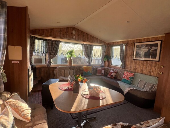 A cozy RV interior with a sofa, dining table, and a kitchen area.