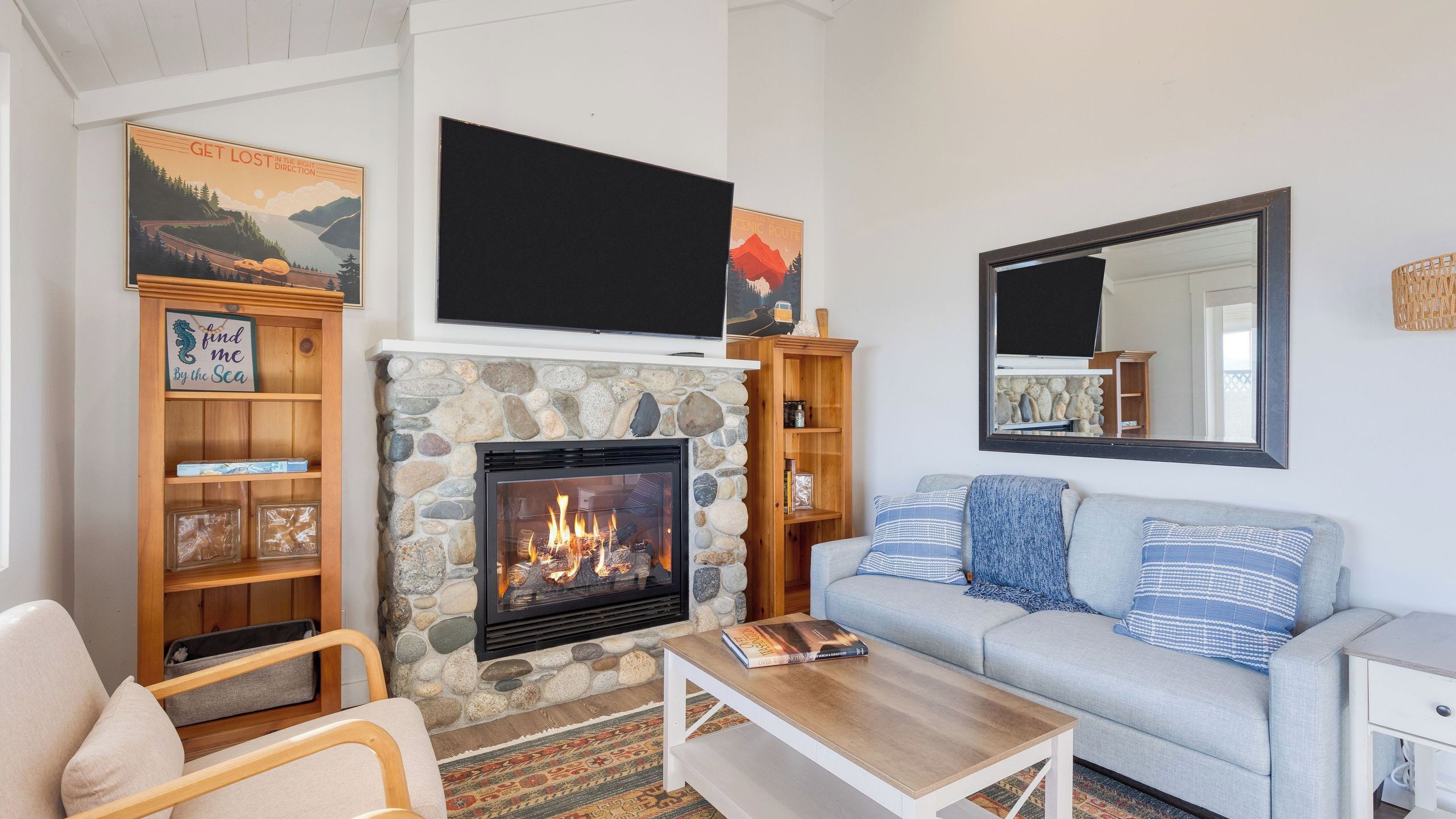 Una sala de estar con chimenea de piedra, un sofá, una mesa de centro y un televisor sobre la chimenea.