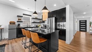 A modern kitchen with a central island, stainless steel appliances, and pendant lighting.