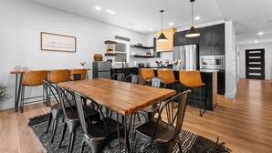 A modern kitchen with a central island, built-in appliances, and a dining area with a wooden table and chairs.