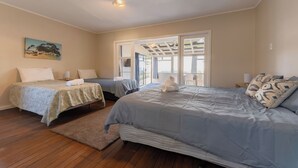 A bedroom with two beds, a large window, and a painting on the wall. - Waterfront | Great Views | Affordable | Unit 3 - KK61643 (Kaikoura)