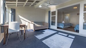 A room with a desk, chair, sofa, and a large window with curtains. - Waterfront | Great Views | Affordable | Unit 3 - KK61643 (Kaikoura)