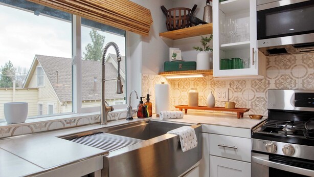 A modern kitchen with a stainless steel sink, a built-in oven, and a microwave.