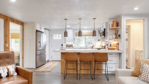 A modern kitchen with a central island, bar stools, and pendant lighting.