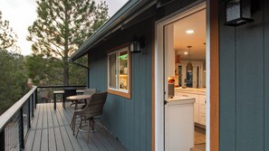 A wooden deck with wicker chairs, a small table, and a view of the surrounding forest. - Cozy 2BR Fawnskin Cabin Big Bear Lake, Hiking Trails & Snow Summit Nearby (Fawnskin)