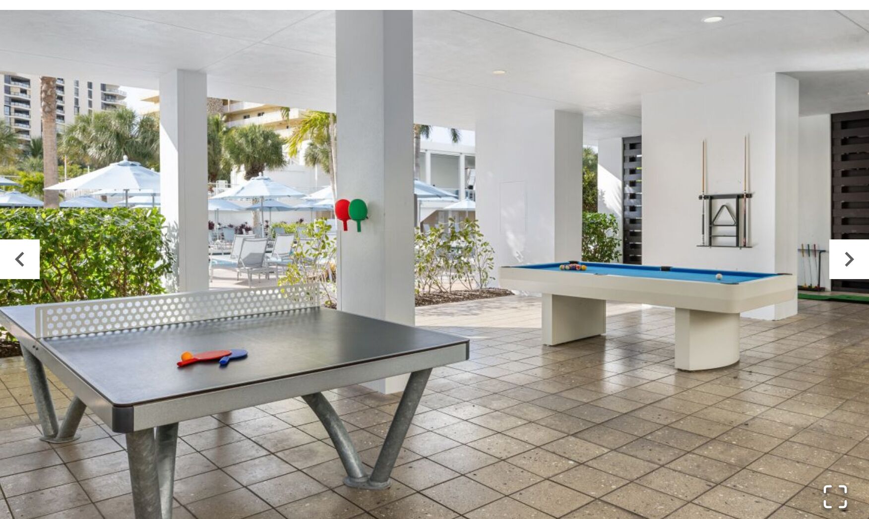 Un espacio recreativo al aire libre con mesa de ping pong y mesa de billar.