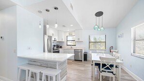 A modern kitchen with white cabinetry, a central island, and pendant lighting.