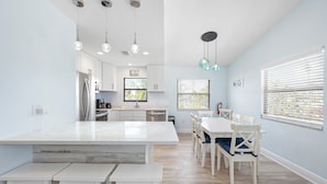 A spacious kitchen with white cabinetry, a large island, and pendant lighting.