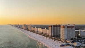 A coastal cityscape with high-rise buildings adjacent to a sandy beach. - Relax at Panama City Beach Balcony, Parking, Walk to Dining (Panama City Beach)