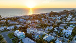 Un quartier résidentiel situé sur la côte, avec des maisons, une plage et un coucher de soleil.
