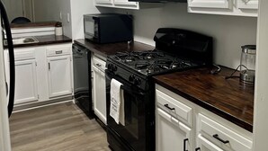 A kitchen with white cabinets, a black stove, a microwave, and a dishwasher.