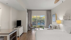 A hotel room with a bed, a TV on a dresser, a chair, a small table, and a window with curtains. - Resort Condo Steps to Beach Pool, Hot Tub, Tennis, Golf Sandestin, Miramar Beach (Miramar Beach)