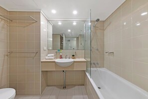 A modern bathroom with a glass shower enclosure, a white sink, and a bathtub.