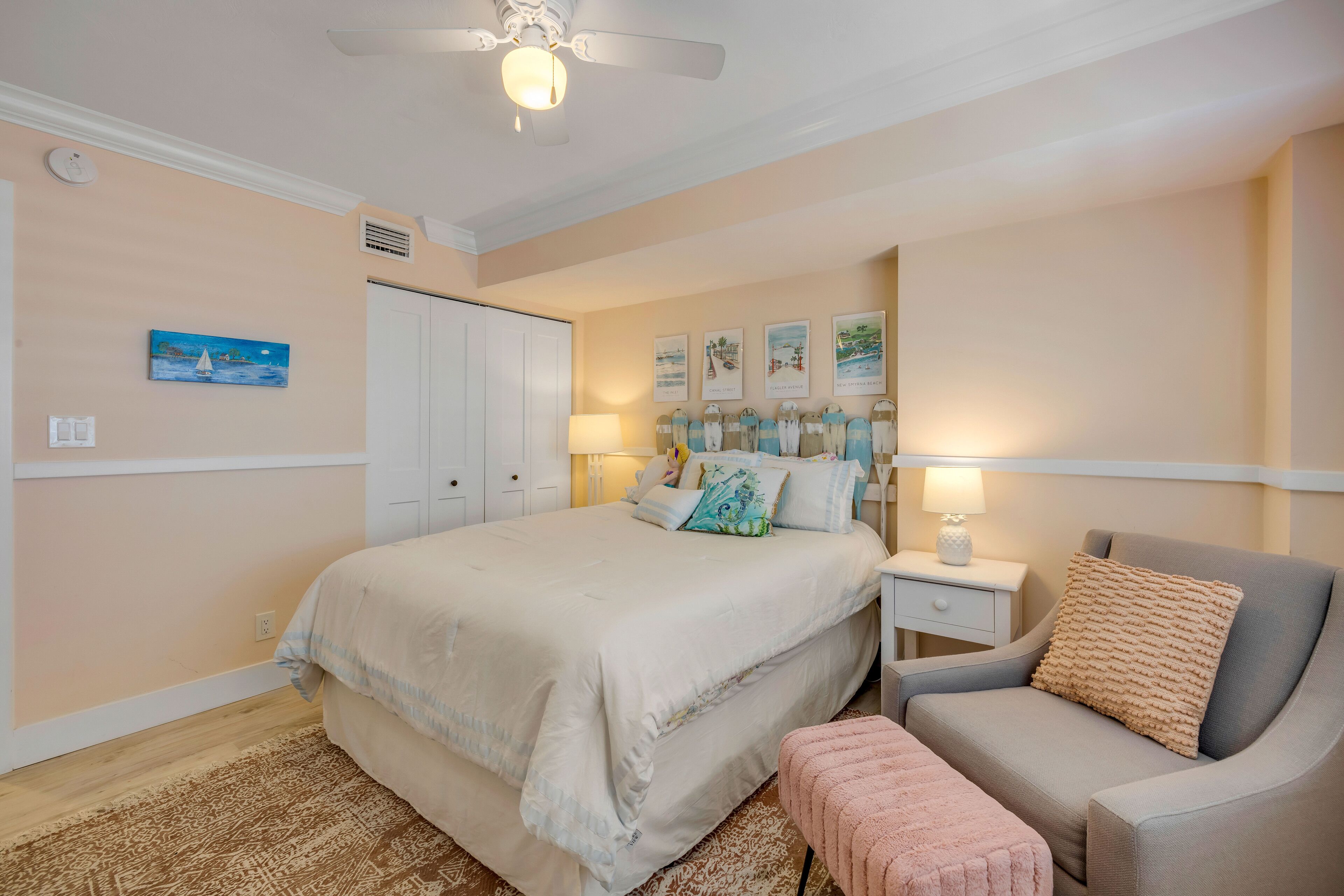 A bedroom with a bed, a chair, a nightstand, and wall art.