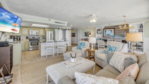 A spacious living area with a large TV, a kitchen with modern appliances, a dining area, and a cozy seating space with a fireplace.