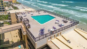 A rooftop pool with a view of the ocean, surrounded by buildings.