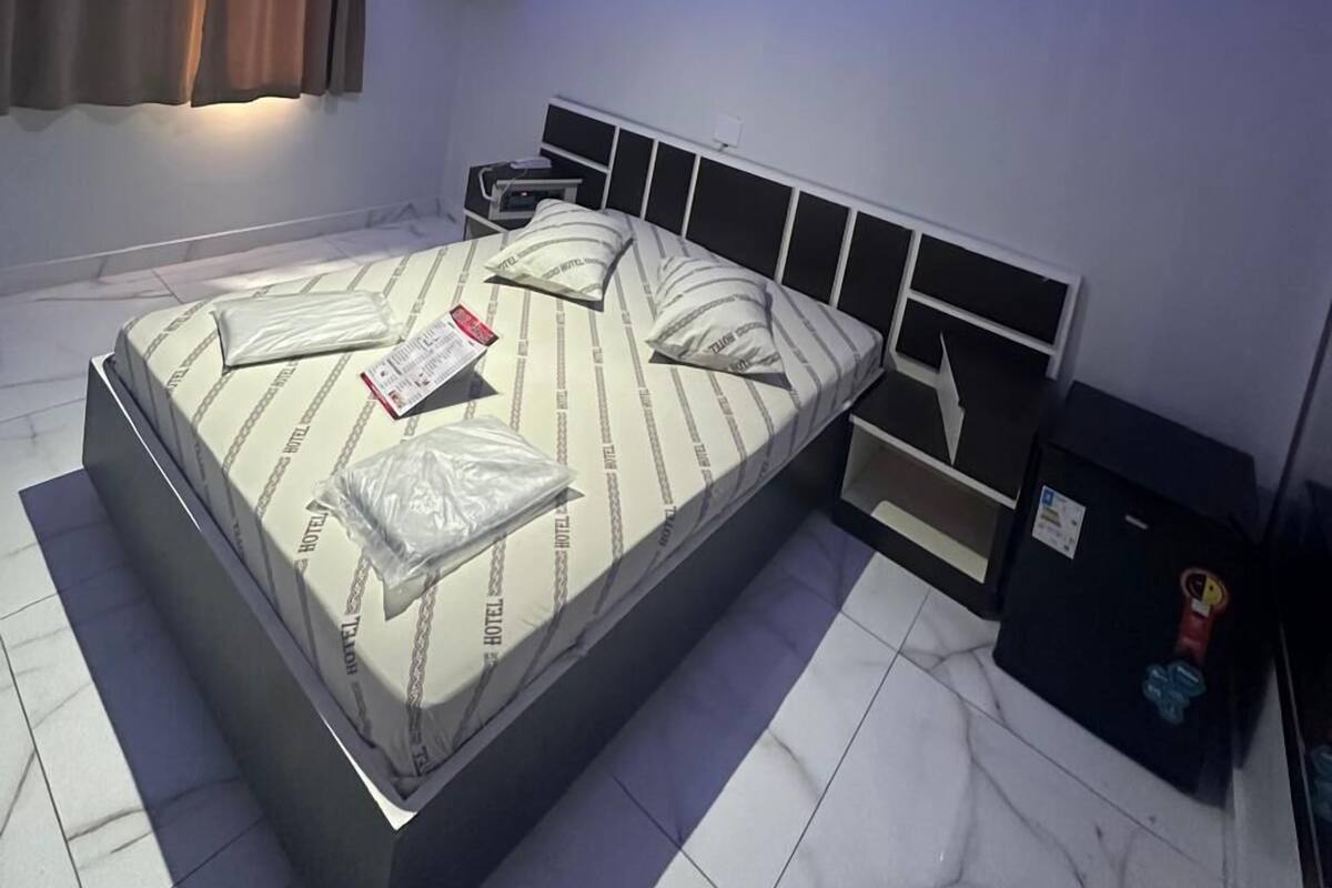 A modern bedroom with a large bed, a TV mounted on the wall, and a ceiling light fixture.