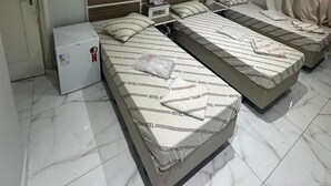 Una habitación de hotel con tres camas, un refrigerador pequeño y una puerta.
