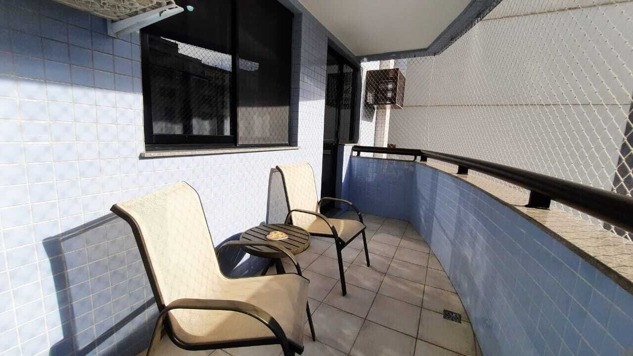 A balcony with two chairs and a small table, a window, and a blue tiled wall.
