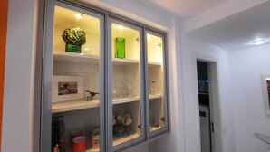 A hallway with a glass-fronted cabinet containing decorative items and glassware. - Hospeda Pluss (Rio de Janeiro)