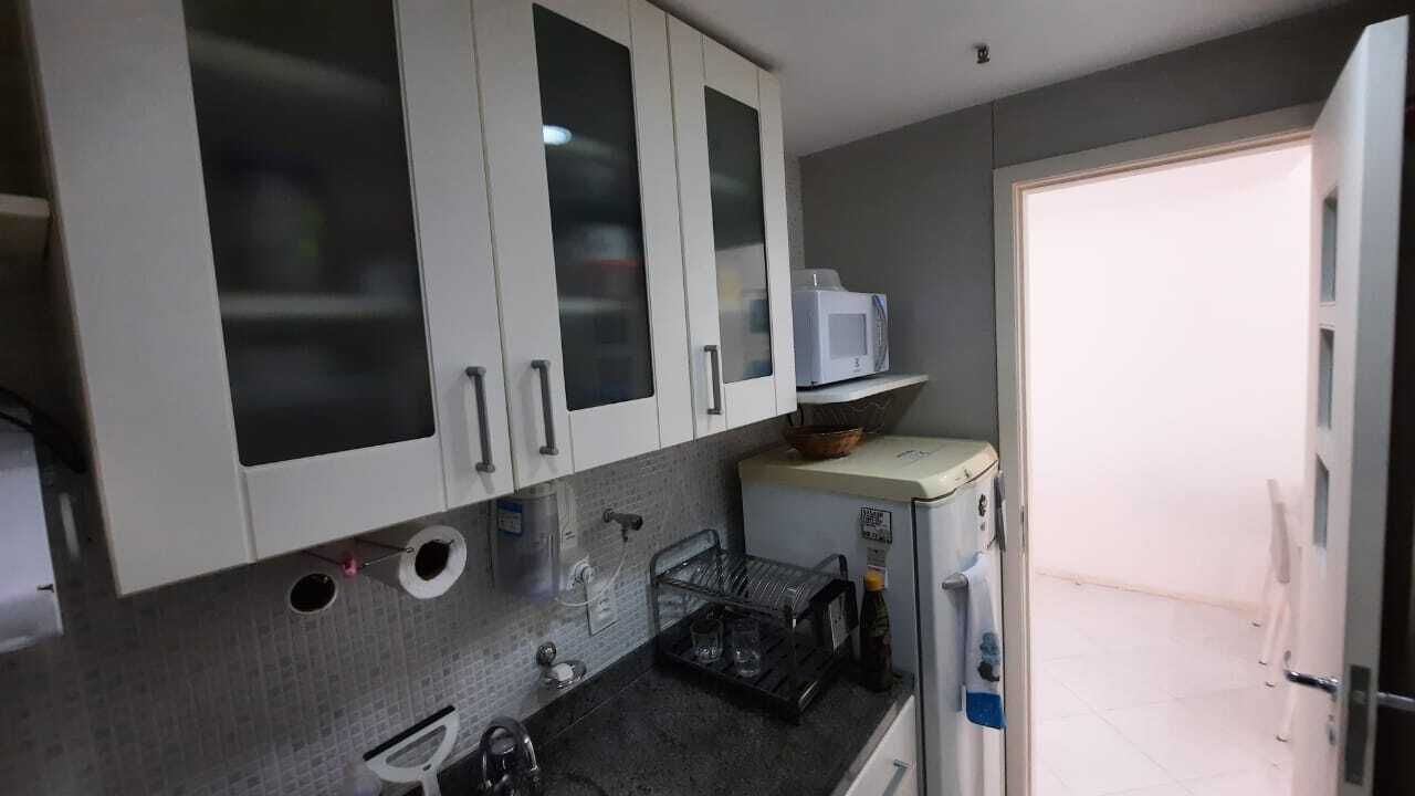 A kitchen with white cabinets, a microwave, a sink, and a countertop.