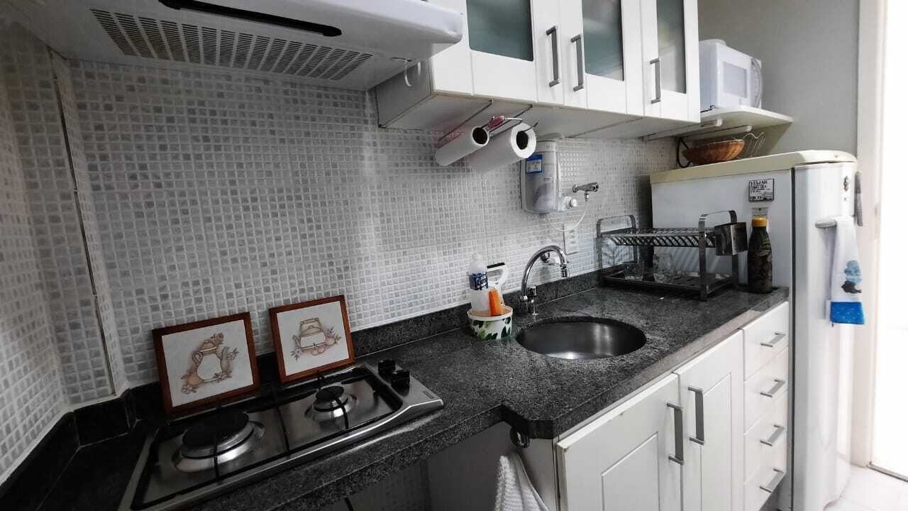 Een keuken met witte kastjes, een zwart aanrecht, een spoelbak en een fornuis.