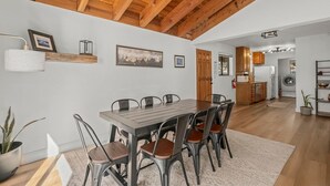 A spacious dining area with a wooden ceiling, a kitchen in the background, and a potted plant on the floor. - Tahoe Getaway near Kings Beach - Sleeps 9 (Kings Beach)