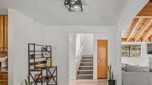 A spacious living area with a wooden staircase, a grey sofa, and a black metal shelf unit. - Tahoe Getaway near Kings Beach - Sleeps 9 (Kings Beach)