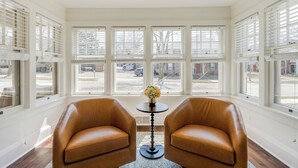 A room with two leather chairs, a small table with a vase, and large windows with shutters. - Charming 5-bedroom house in Cedarburg (Cedarburg)