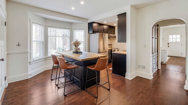 A modern kitchen with a central island, bar stools, and a dining area. - Charming 5-bedroom house in Cedarburg (Cedarburg)