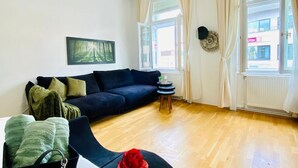 A living room with a dark sofa, a small round table, and a window with curtains.