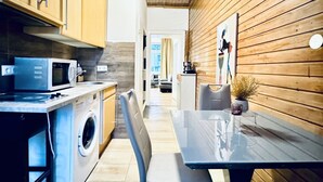 A modern kitchen with a washing machine, microwave, and wooden wall paneling. - Spacious Studio for 4 Near FAC Platz (Vienna)