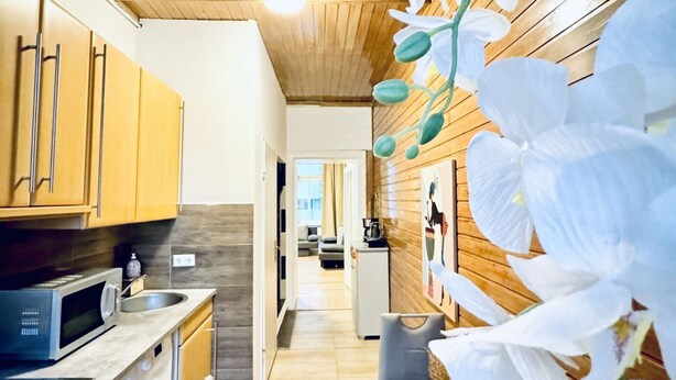 A kitchen with wooden cabinets, a microwave, and a washing machine. - Spacious Studio for 4 Near FAC Platz (Vienna)