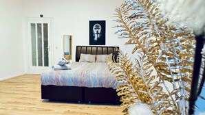 A bedroom with a bed, a door, a framed artwork, and a decorative plant. - Spacious Studio for 4 Near FAC Platz (Vienna)