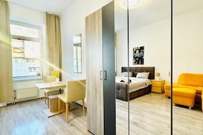 Une chambre à coucher moderne avec un lit, une table de chevet et un fauteuil jaune vif.