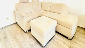 A corner room with a beige sectional sofa and a matching ottoman. - Nice Room in a Shared Apt, 10Min to FAC Platz (Vienna)