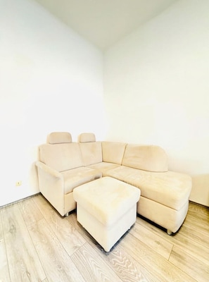 A corner room with a beige sectional sofa and a matching ottoman.