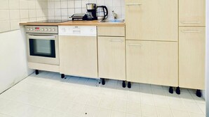 Eine kleine Küche mit einbauendem Ofen, Geschirrspüler und Mikrowelle auf der Arbeitsplatte.